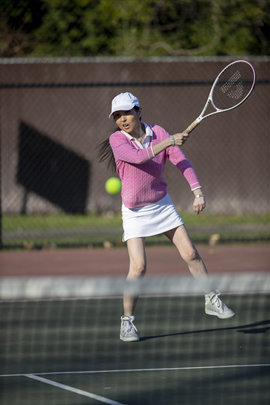 Female tennis player making a back swing on the court.