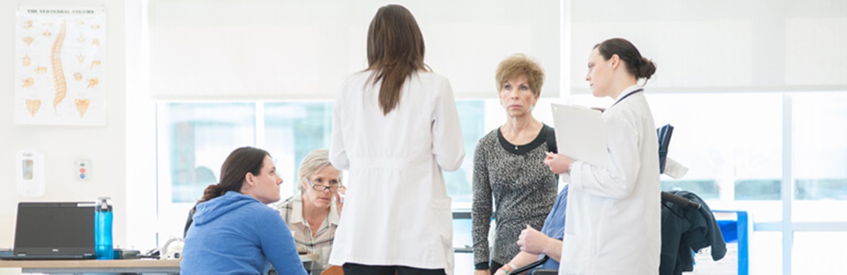 Team of professionals gathered around a nurse's station.