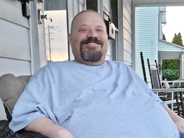 Doug Mundorf smiles on his porch after inpatient rehabilitation.