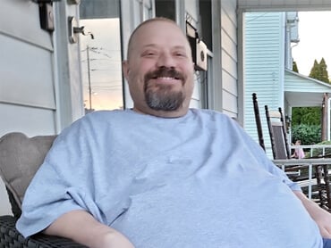 Doug Mundorf smiles on his porch after inpatient rehabilitation.