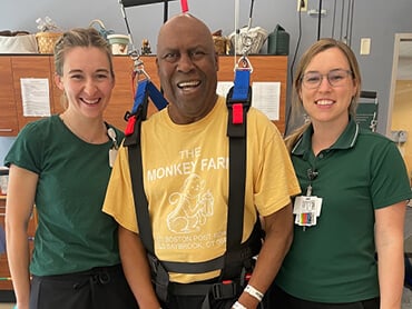 Victor Berry smiles with two of his therapists by his side.